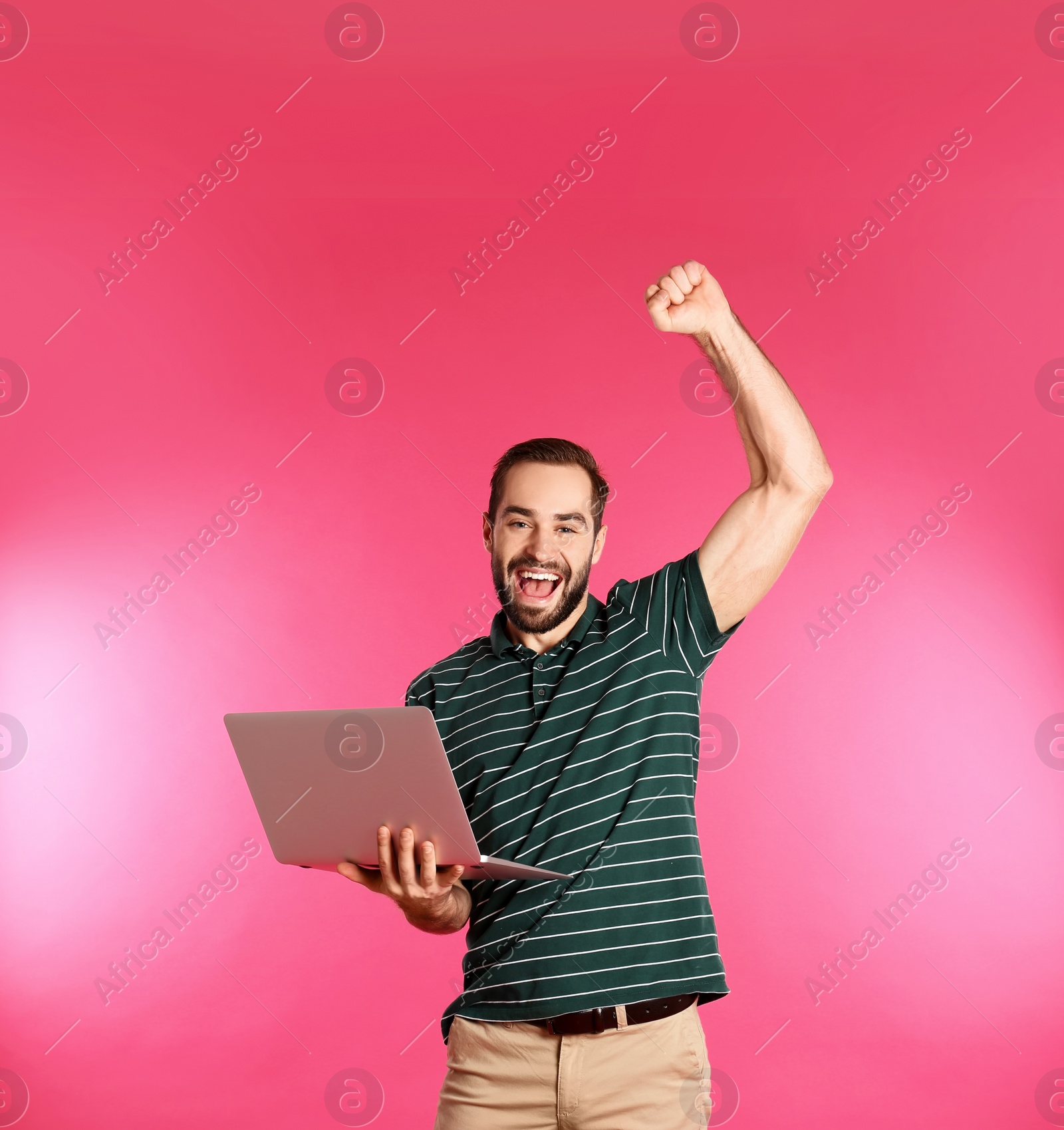 Photo of Emotional young man with laptop celebrating victory on color background