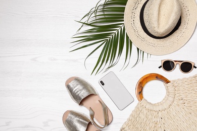 Flat lay composition with beach bag and accessories on white wooden background, space for text