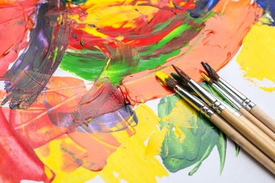 Photo of Set of brushes with different paints on artwork. Space for text