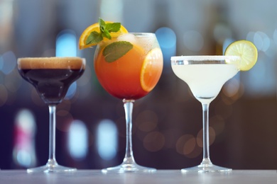 Photo of Row of different fresh alcoholic cocktails on bar counter