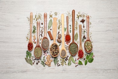 Different natural spices and herbs on light wooden table, flat lay