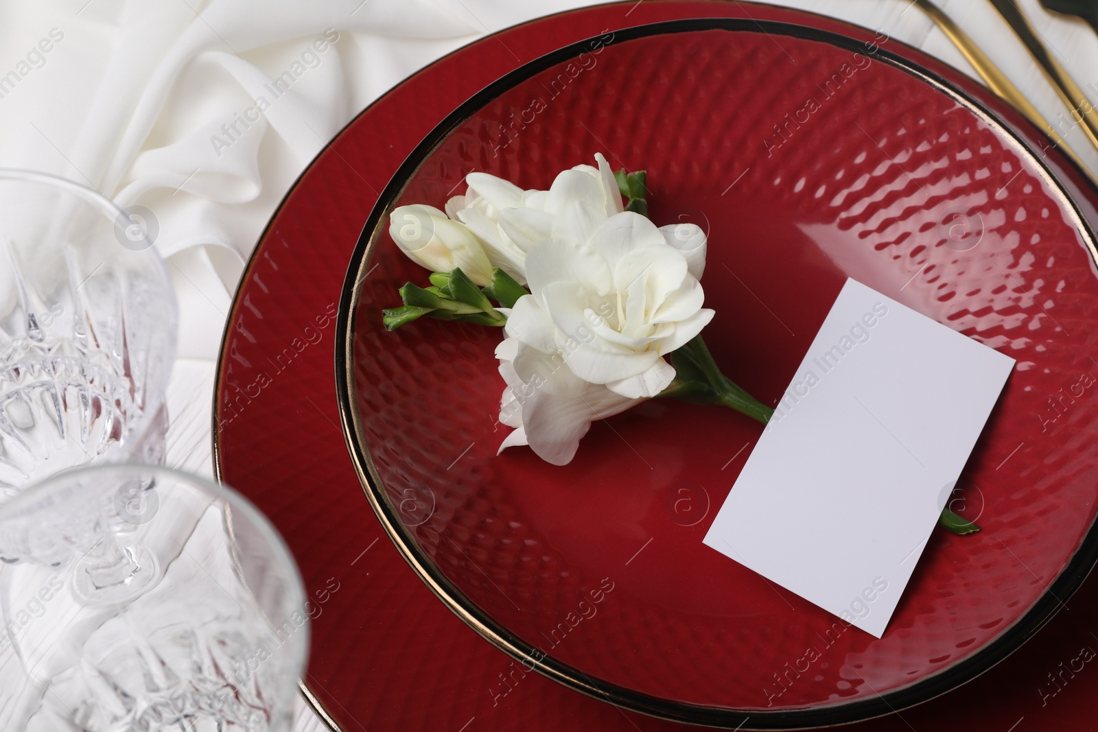 Photo of Stylish table setting. Dishes, glasses, blank card and flower, above view