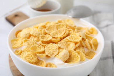 Photo of Breakfast cereal. Tasty corn flakes with milk in bowl on table, closeup