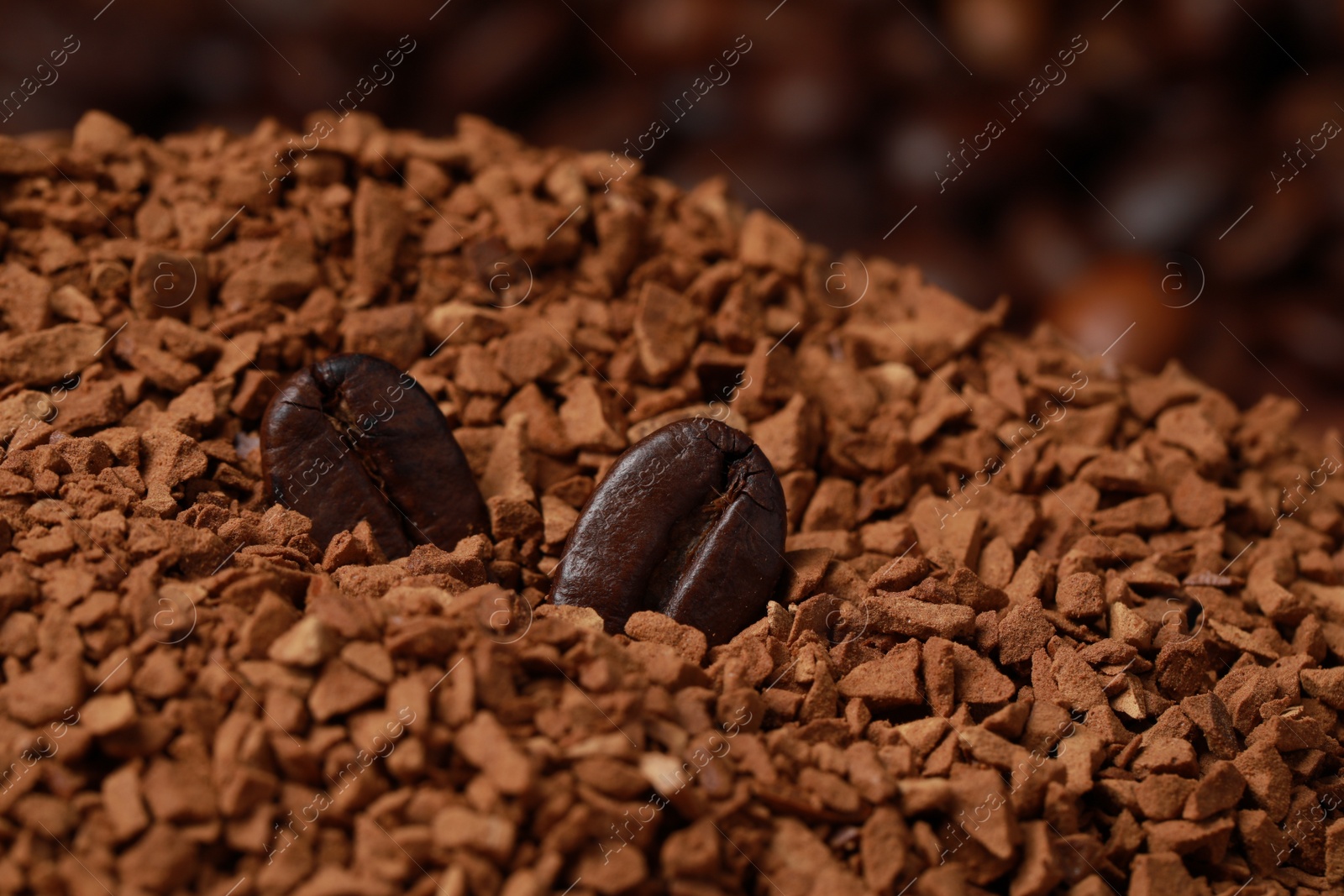 Photo of Roasted beans on pile of dry instant coffee, closeup view