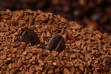 Roasted beans on pile of dry instant coffee, closeup view