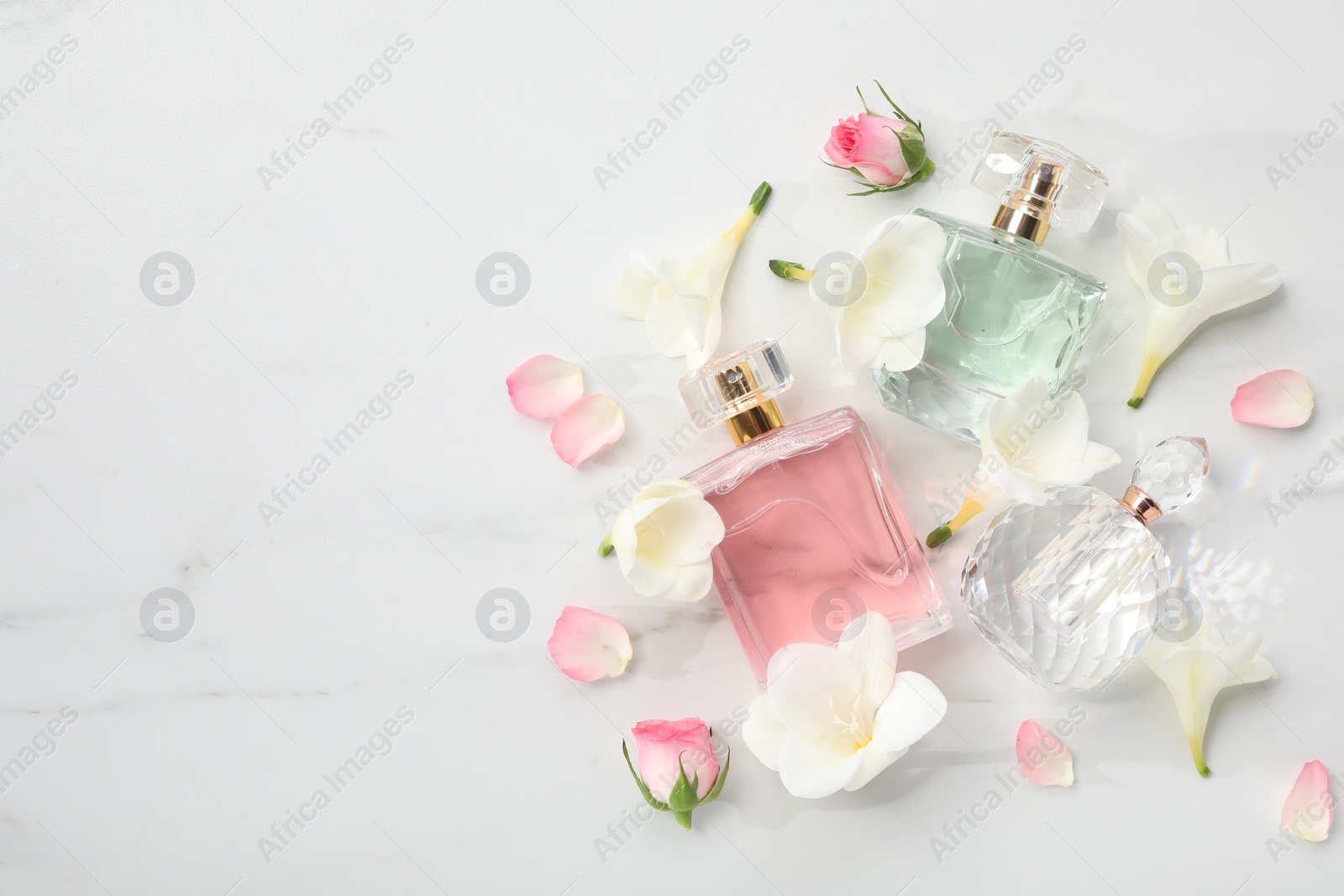 Photo of Luxury perfume and floral decor on white marble table, flat lay. Space for text