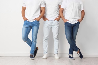 Photo of Group of young men in jeans near light wall