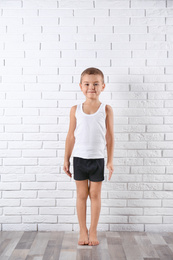 Cute little boy in underwear near white brick wall