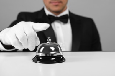 Photo of Butler ringing service bell at white table, closeup