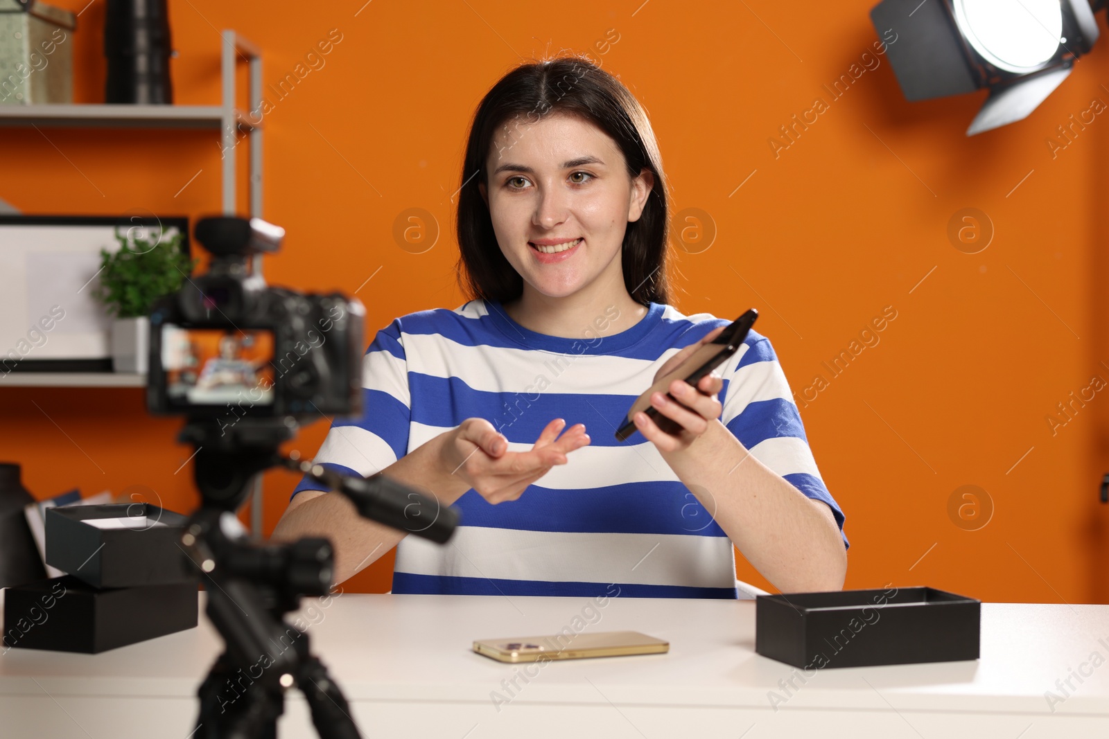 Photo of Smiling technology blogger recording video review about smartphones at home