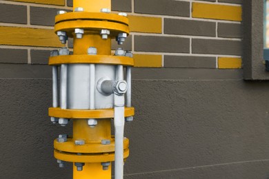 Photo of Yellow gas pipe with valve near brick wall outdoors, space for text