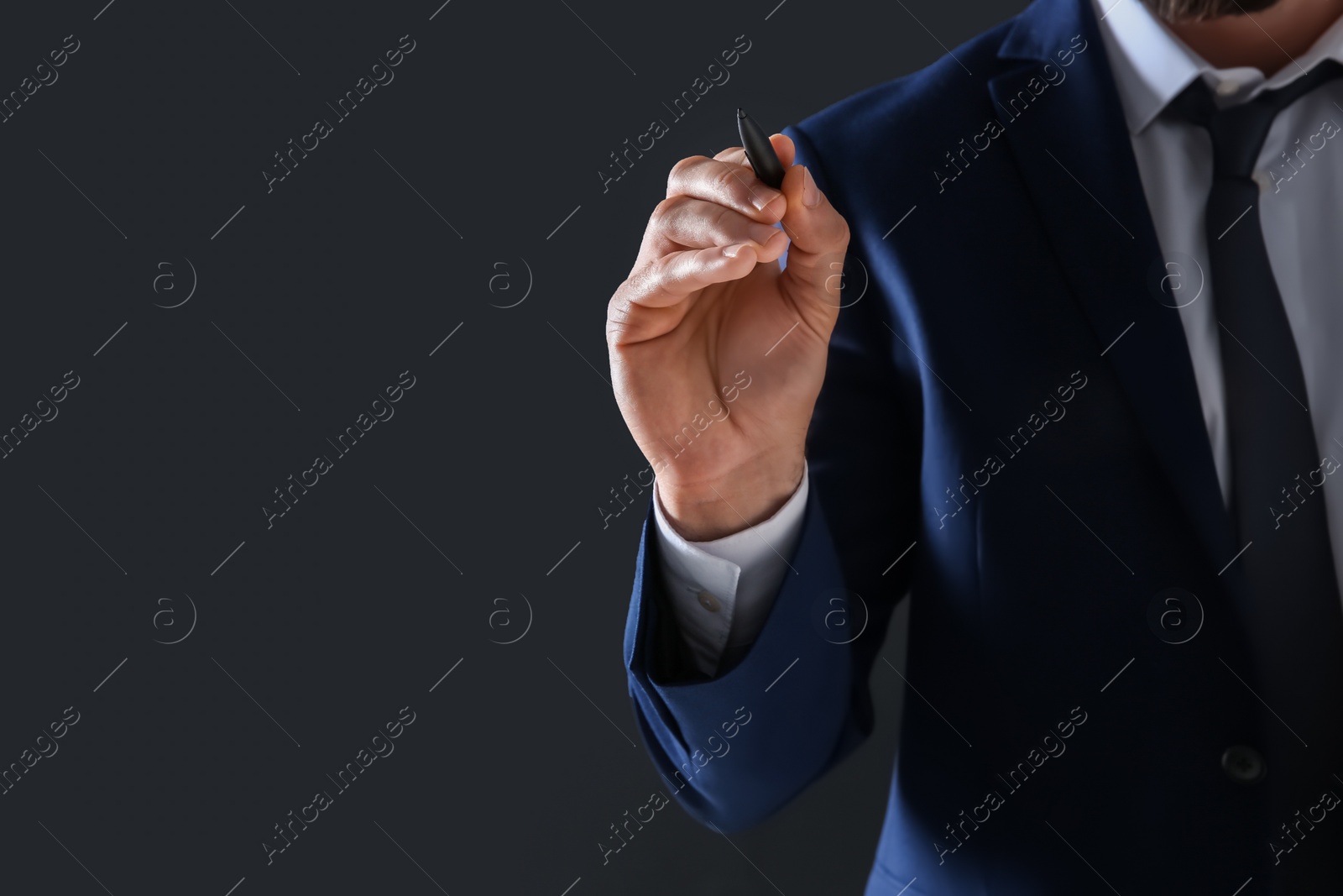 Photo of Businessman holding pen in hand on dark background