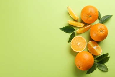 Photo of Delicious oranges on green background, flat lay. Space for text