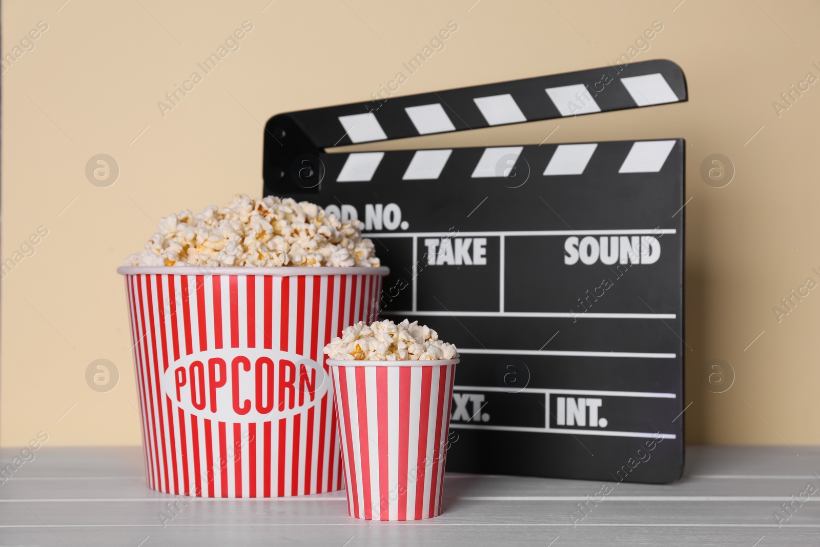 Photo of Delicious popcorn and clapperboard on wooden table