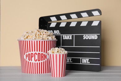 Photo of Delicious popcorn and clapperboard on wooden table