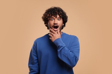 Handsome surprised man on beige background, space for text