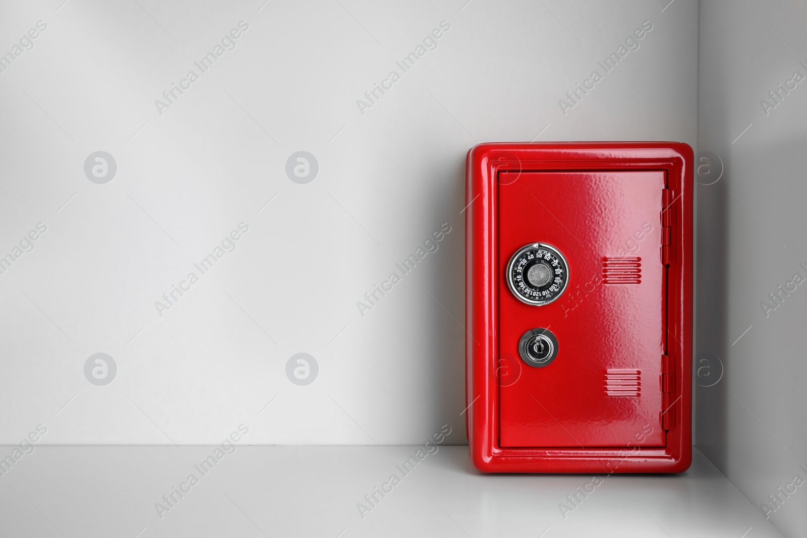 Photo of Red steel safe with mechanical combination lock on shelf. Space for text