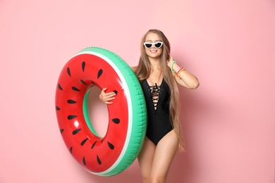Photo of Beautiful young woman in bikini with inflatable ring against color background