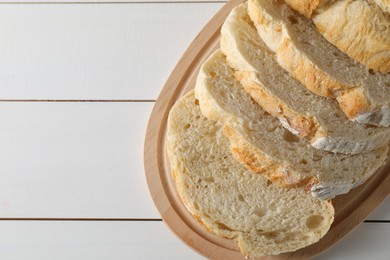 Photo of Freshly baked cut sourdough bread on white wooden table, top view. Space for text