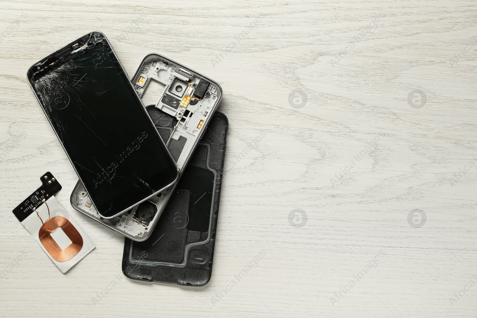 Photo of Damaged smartphone on wooden background, flat lay with space for text. Device repairing