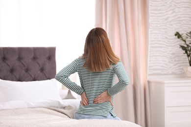 Photo of Young woman suffering from back pain at home