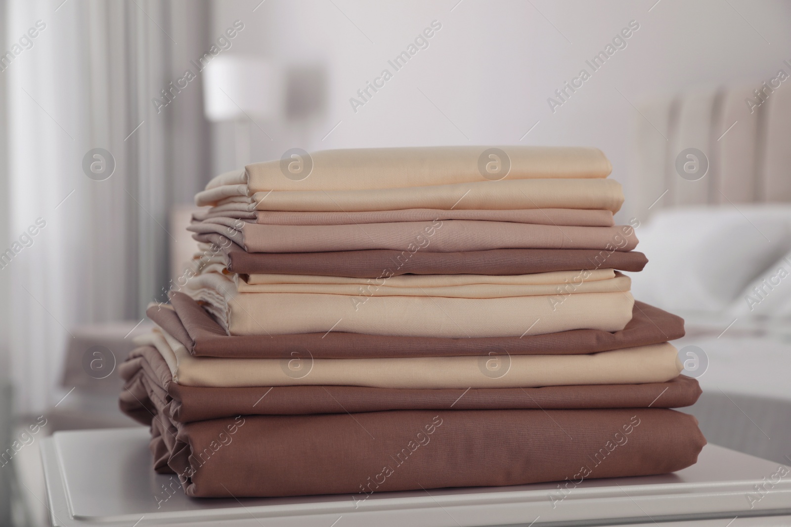 Photo of New clean folded bed linens on table indoors