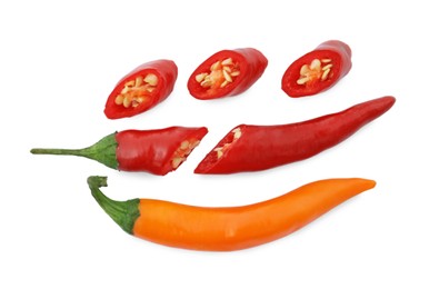 Cut and whole hot chili peppers on white background, flat lay