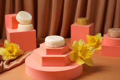 Photo of Stylish presentation of dry shampoo bars and daffodil flowers on light brown table
