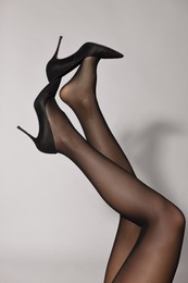 Photo of Woman with beautiful long legs wearing black tights and stylish shoes on light background, closeup
