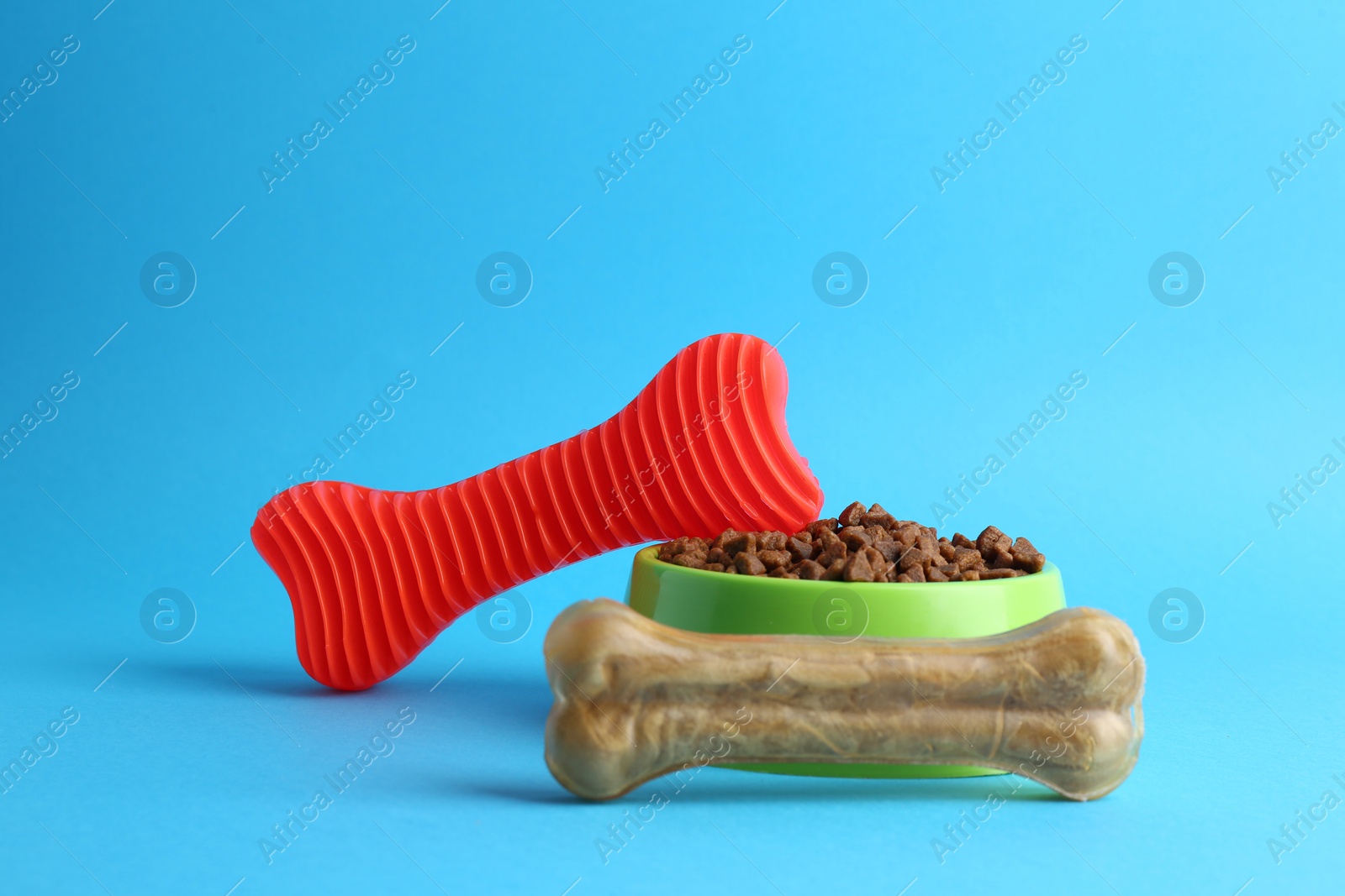 Photo of Pet toy, dog treat and feeding bowl on light blue background