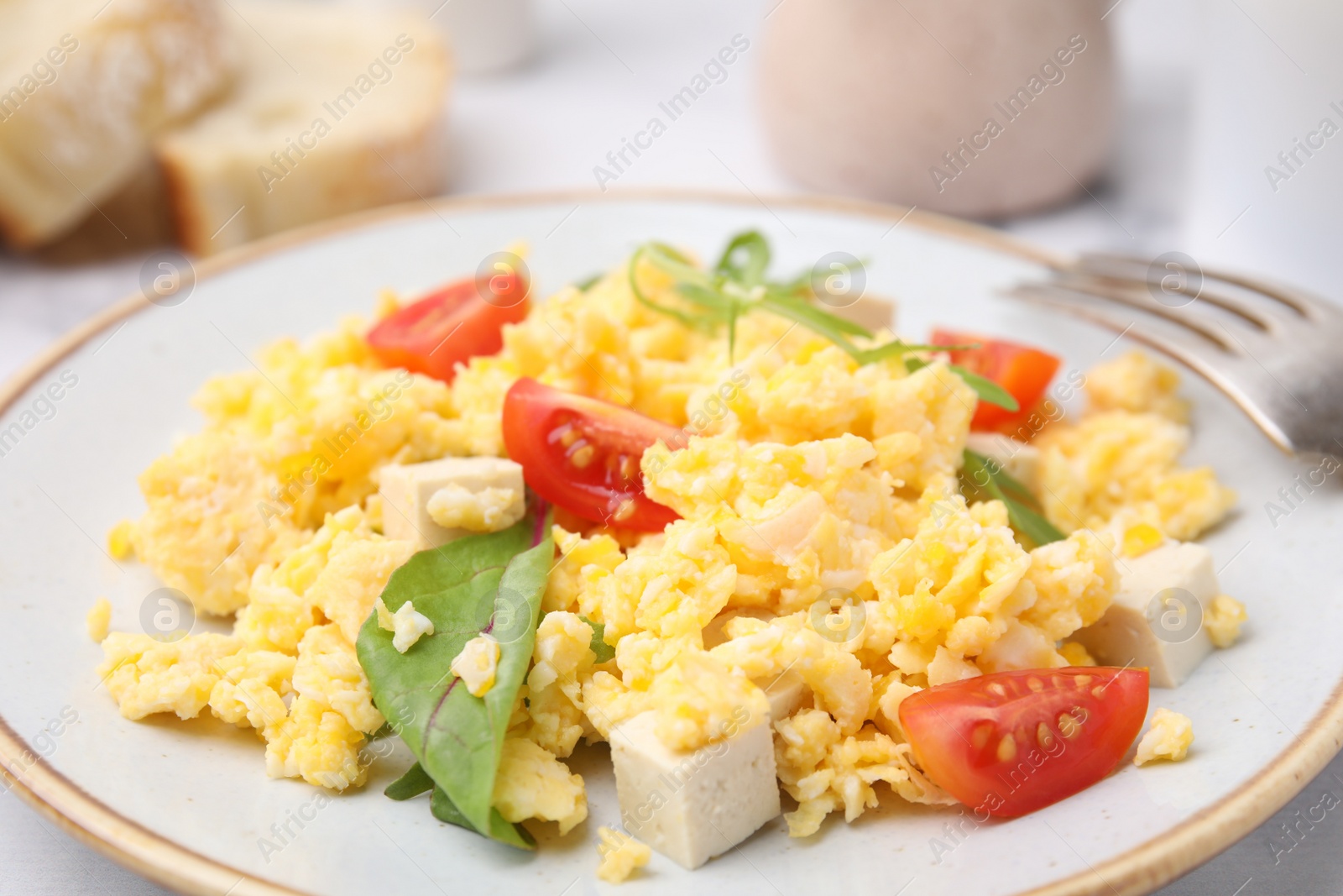 Photo of Plate with delicious scrambled eggs, tofu and tomatoes on table, closeup