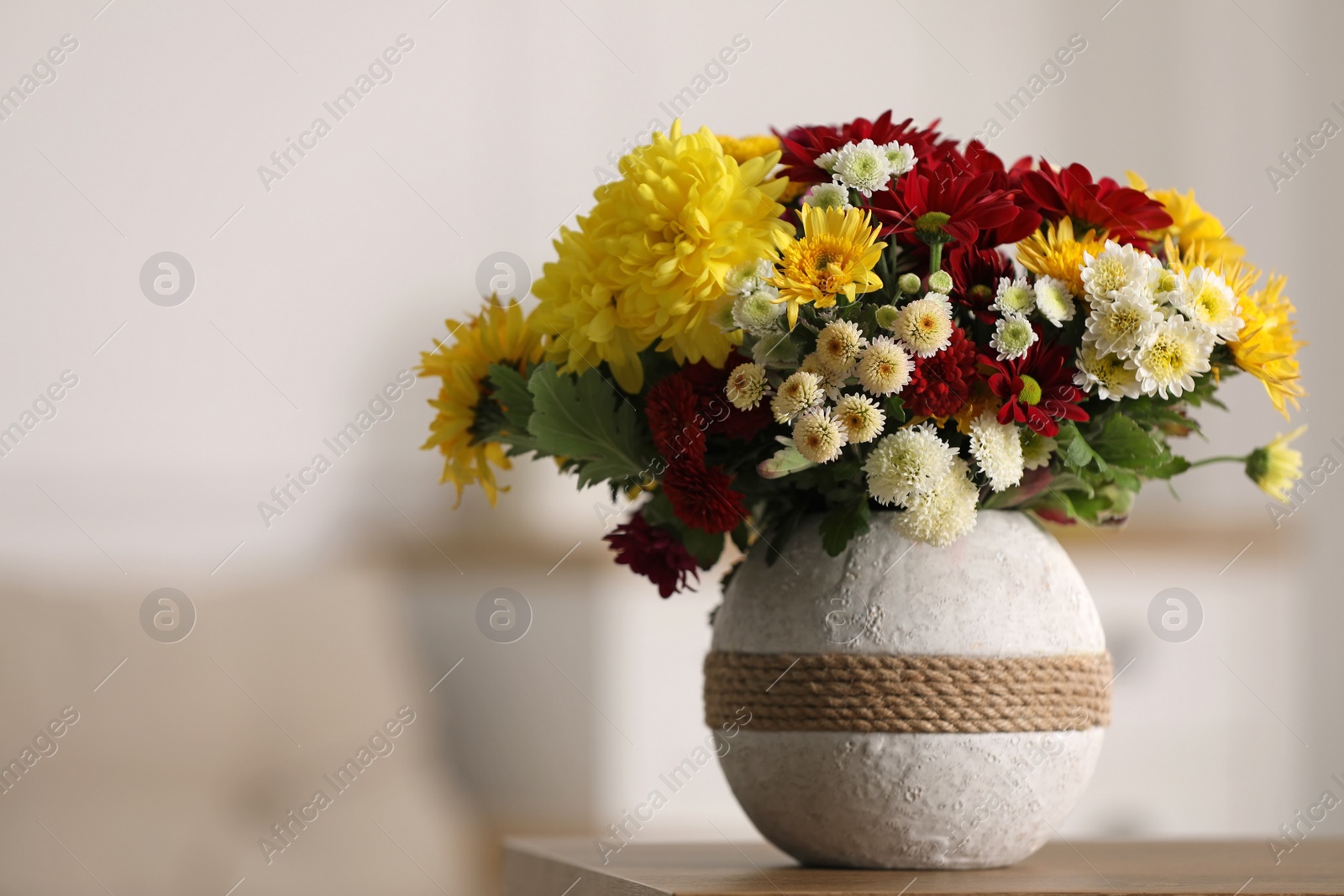 Photo of Bouquet of beautiful chrysanthemum flowers on table in room, space for text