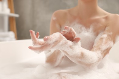 Woman taking bath with shower gel in bathroom, closeup