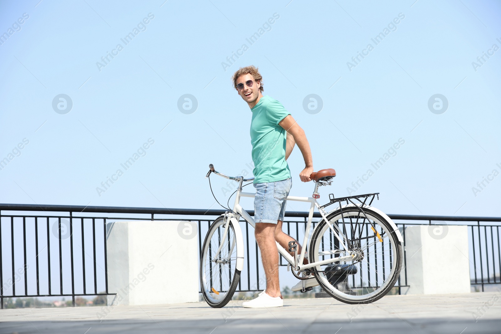 Photo of Handsome young man with bicycle outdoors on sunny day