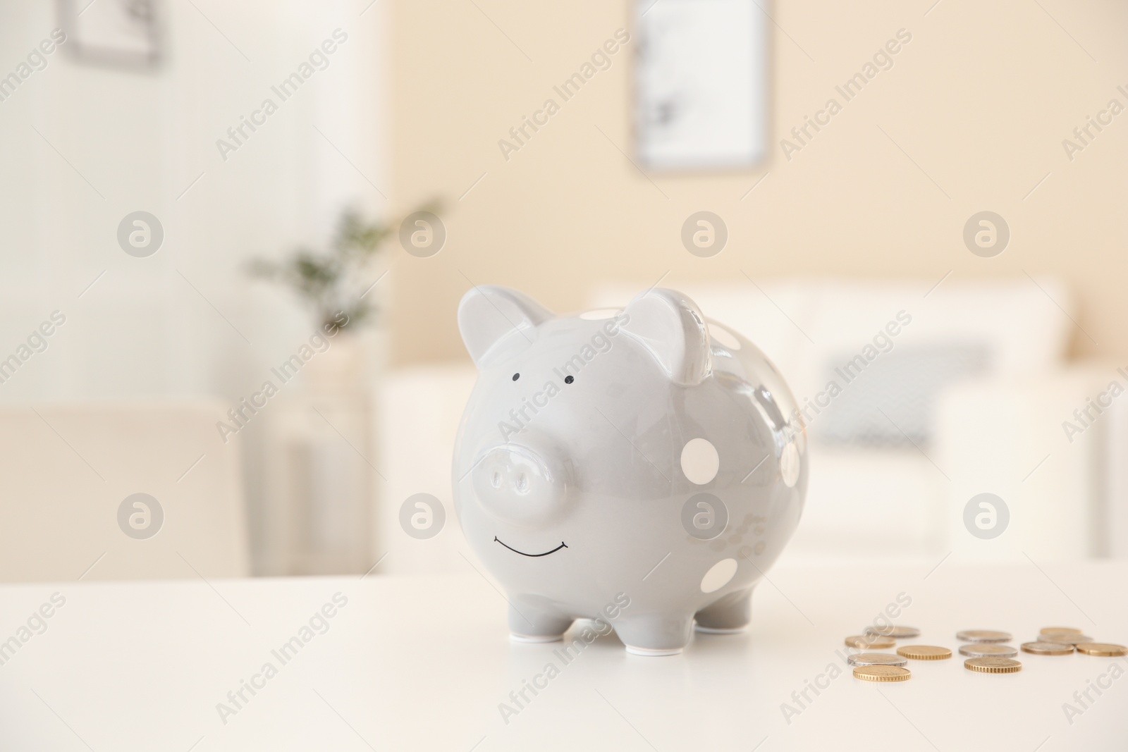 Photo of Piggy bank and coins on table against blurred background. Space for text