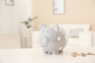 Piggy bank and coins on table against blurred background. Space for text