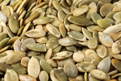 Photo of Many peeled pumpkin seeds as background, closeup