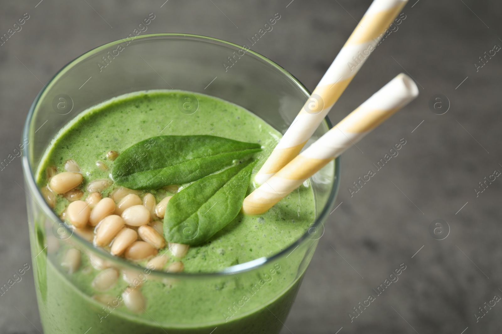 Photo of Glass of healthy green smoothie with fresh spinach on grey table, closeup view