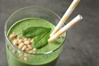 Glass of healthy green smoothie with fresh spinach on grey table, closeup view