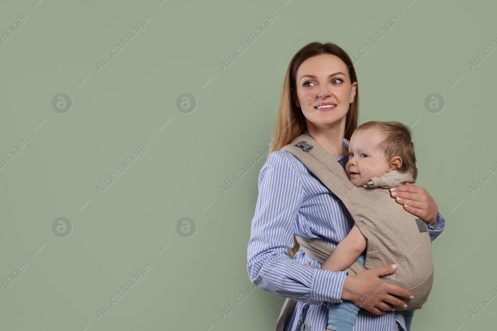 Photo of Mother holding her child in sling (baby carrier) on olive background. Space for text