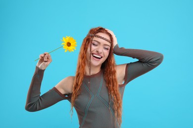 Photo of Beautiful young hippie woman with sunflower on light blue background