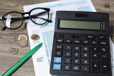 Tax accounting. Calculator, document, pen and coins on wooden table, closeup