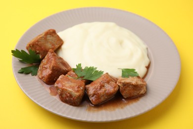 Photo of Delicious goulash with mashed potato on yellow background, closeup