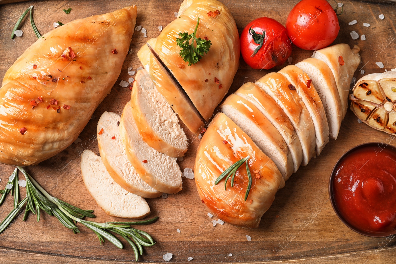 Photo of Fried chicken breasts and sauce served on wooden board, top view