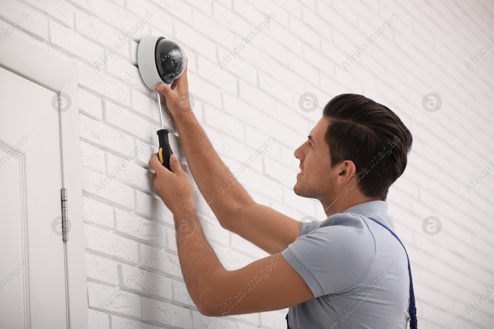 Photo of Technician installing CCTV camera on wall indoors