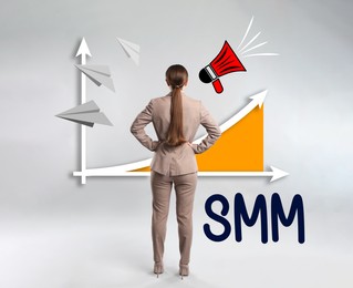 Image of Social media marketing. Young woman in business attire, abbreviation SMM and chart on light grey background