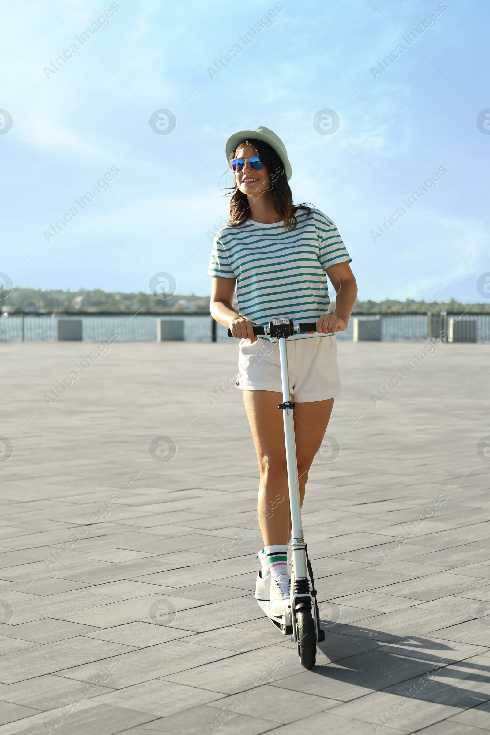 Photo of Young woman riding kick scooter along city street