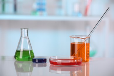 Photo of Laboratory analysis. Different glassware with liquids on white table against blurred background