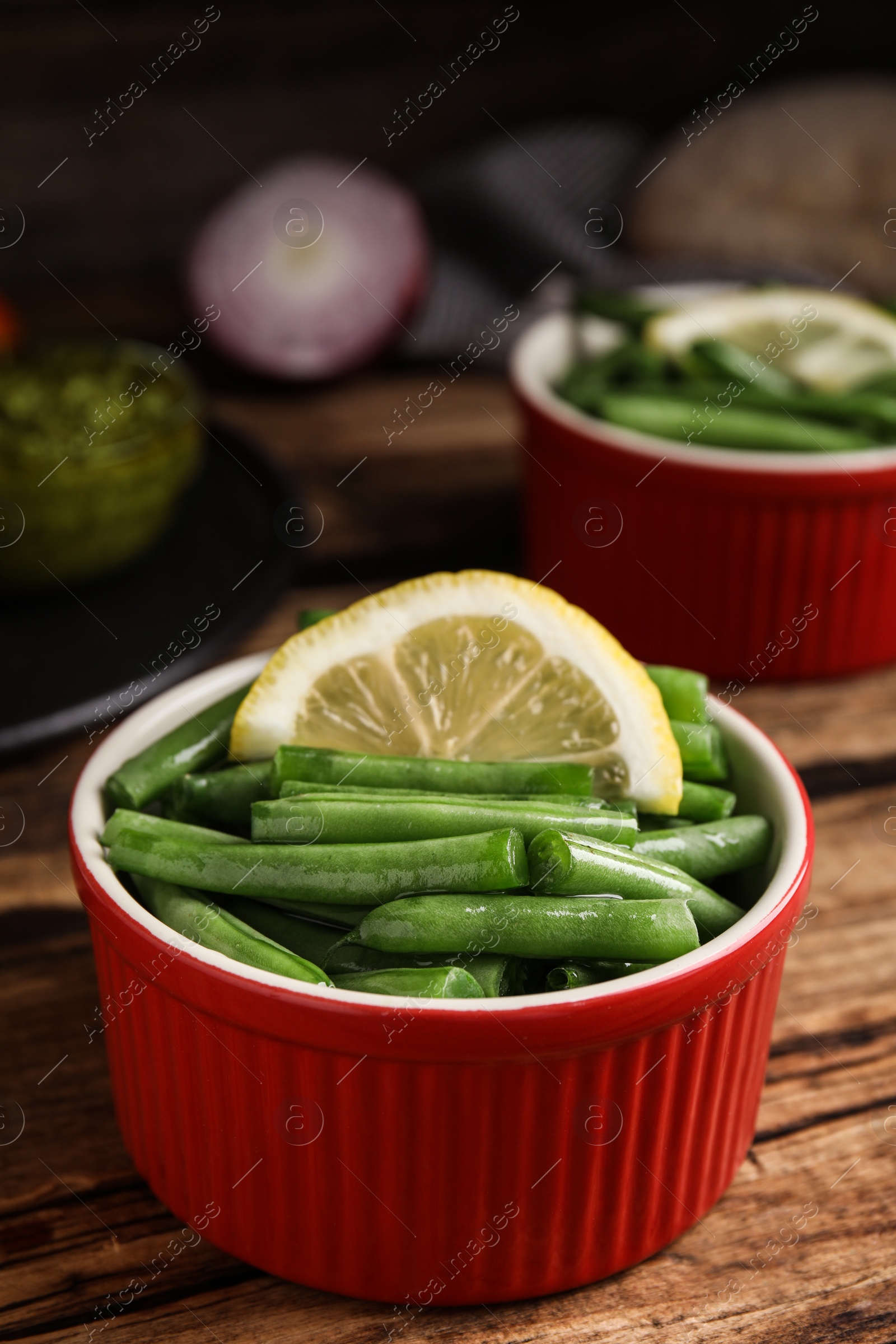 Photo of Raw green beans with lemon on wooden table, closeup