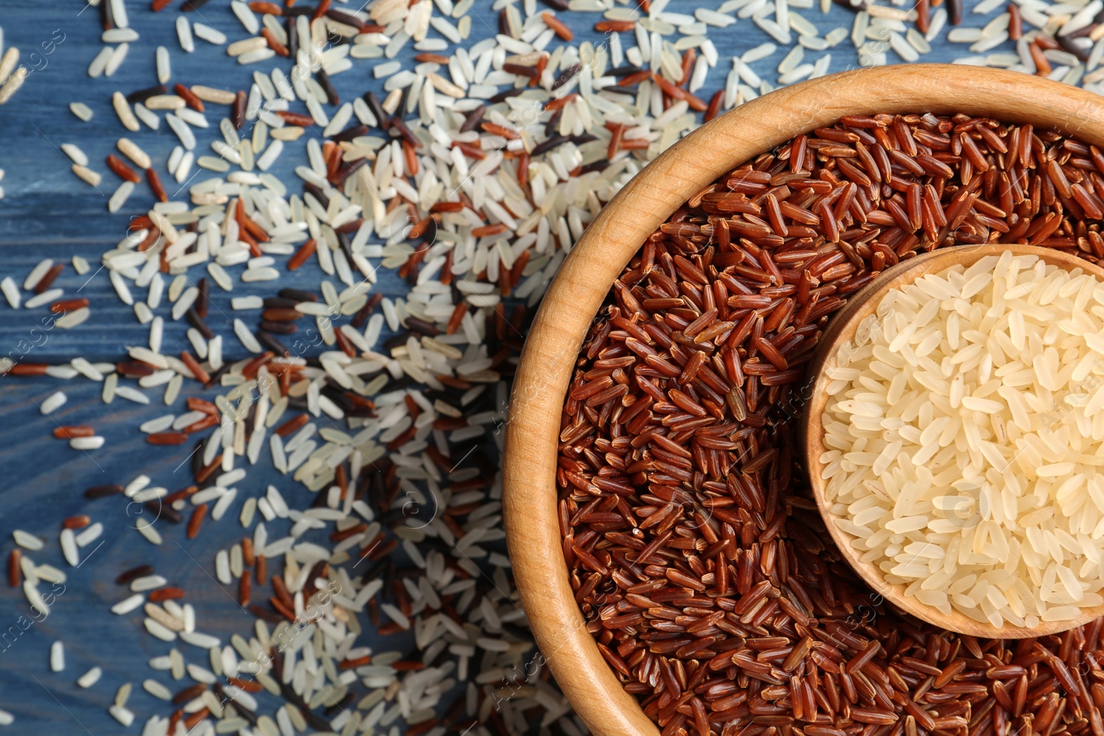 Photo of Flat lay composition with brown and other types of rice on color wooden background